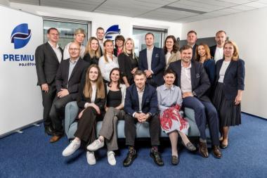 Společná fotografie týmu PREMIUM Pojišťovny v kanceláři – vedení a zaměstnanci pózují před firemním logem
